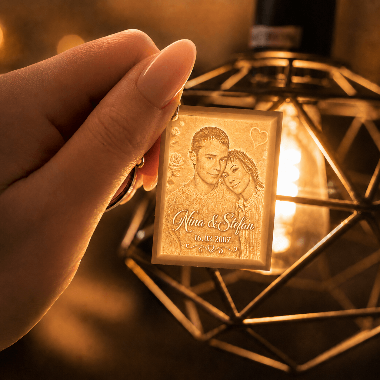 Kleiner personalisierter Lithophane-Schlüsselanhänger mit Paarfoto und Namen, in der Hand gehalten vor warm leuchtender Lampe