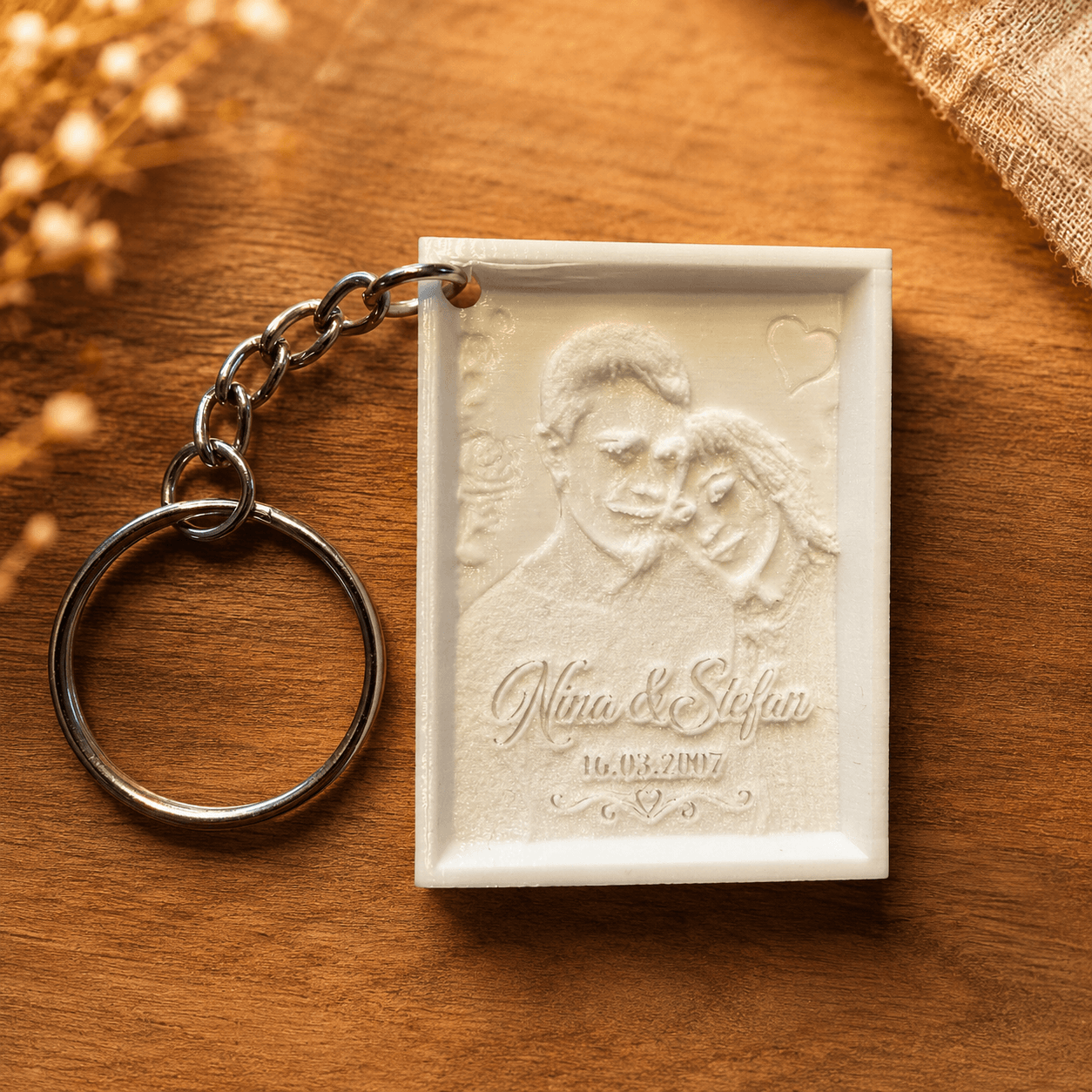 Personalisierter Lithophane-Schlüsselanhänger mit graviertem Paarfoto, Namen und Datum auf einem warmen Holzhintergrund