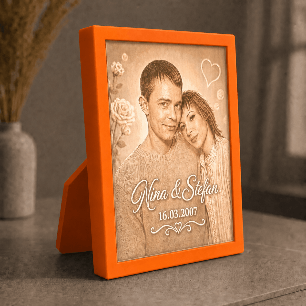 Personalisiertes 3D-Lichtbild Klassik mit Standrahmen in Orange und Wunschfoto von Nina und Stefan, dekorativ in warmer Wohnatmosphäre präsentiert.